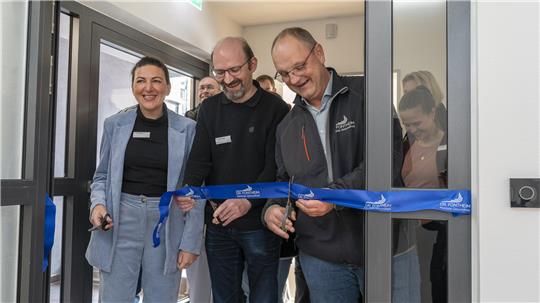 Drei Personen schneiden ein Band durch und eröffnen so die neue Station.