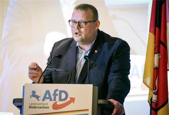 Ein Mann steht an einem Rednerpult und spricht in ein Mikro.