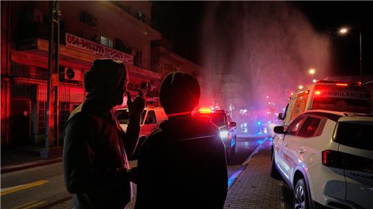 Anwohner beobachten die Arbeit der Rettungskräfte am Ort eines Raketeneinschlags in Tel Aviv.