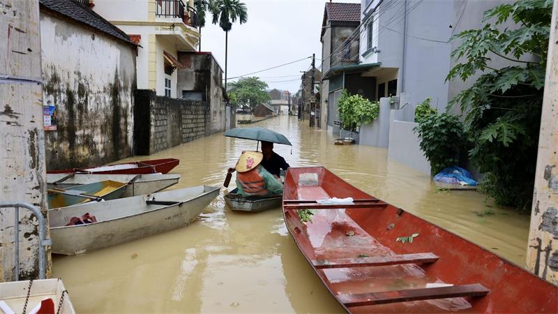 Anwohner fahren mit einem Boot durch ein überflutetes Dorf in Vietnam.