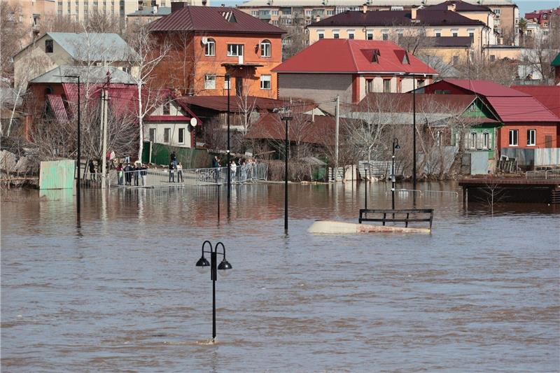 Hochwasserlage in Russland bleibt angespannt Anwohner stehen an einer Absperrung und beobachten ein überschwemmtes Gebiet im russischen Orenburg.