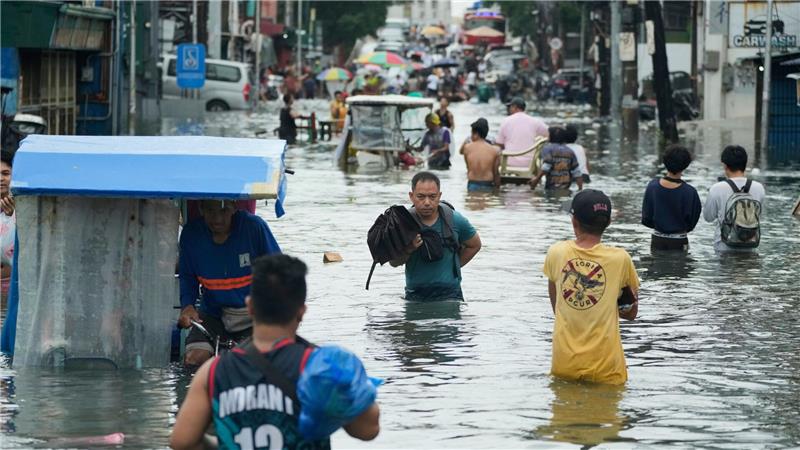 Bilder des Tages Anwohner waten durch eine überschwemmte Straße auf den Philippinen.