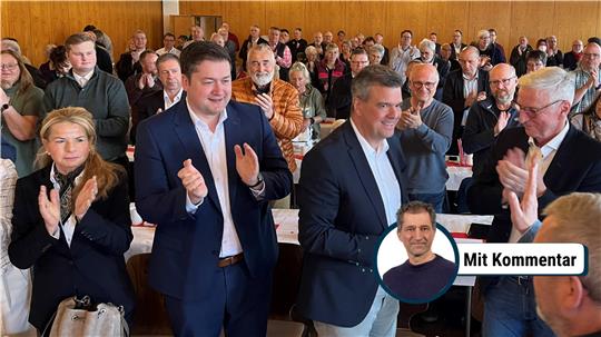 Die Menschen in einem Saal stehen auf und applaudieren.