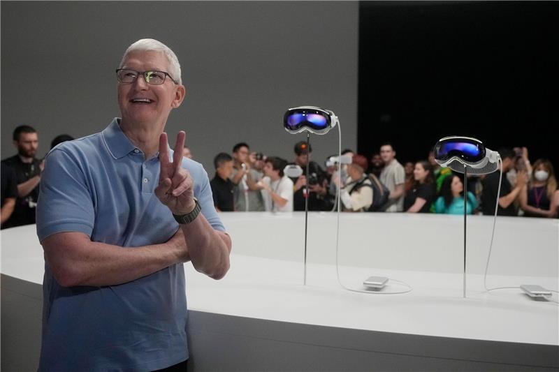 Apple-CEO Tim Cook posiert neben den neuen Vision Pro Headsets auf dem Firmencampus in Cupertino.