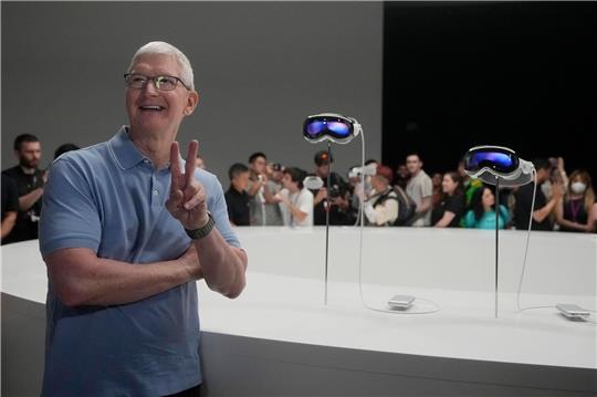 Apple-CEO Tim Cook posiert neben den neuen Vision Pro Headsets auf dem Firmencampus in Cupertino.