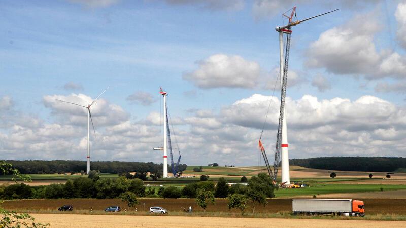 Arbeiten fast im Gleichklang mit zwei Kränen: Im Vordergrund ist das Rotorblatt schon nach oben gezogen, bei der mittleren Anlage hievt es der Kran gerade nach oben.