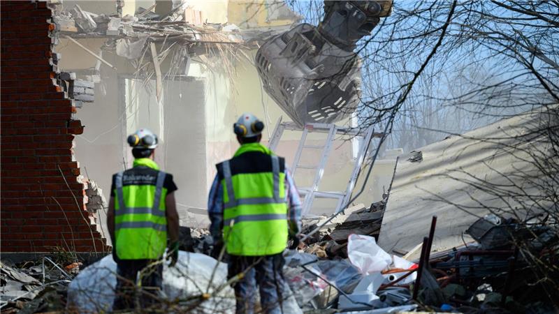 Arbeiter beobachten die Abrissarbeiten eines Baggers am Haus Seeblick am Brodtener Steilufer an der Ostsee.