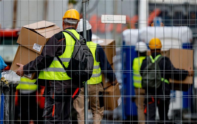 Prognose: Zahl der Arbeitslosen steigt 2023 um 190.000 Arbeiter bringen Material auf eine Baustelle. Wie sich der Arbeitsmarkt einer Prognose zufolge weiter entwickelt.
