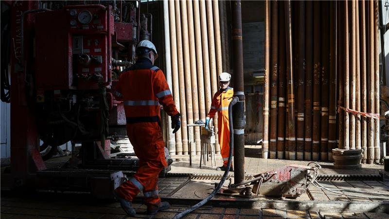 Arbeiter montieren im Bohrturm einen neuen Bohrstrang.