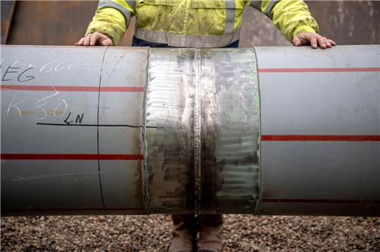 Arbeiter prüfen die letzte Schweißnaht einer weitere Anbindungspipeline für das LNG-Terminal in Wilhelmshaven.