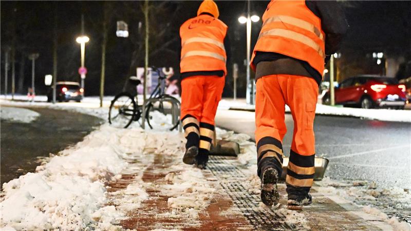 Arbeiter räumen den Schnee mit Schaufeln weg.