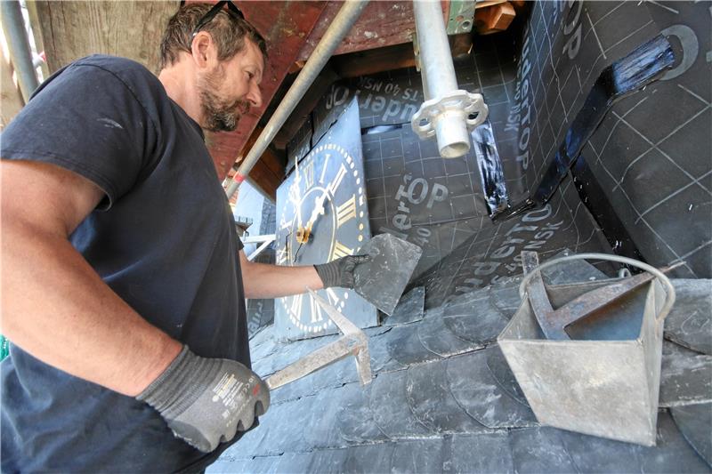 Arbeitsplatz Kirchturmuhr: In den kommenden Wochen sind die Dachdecker damit beschäftigt, Tausende neue Schieferplatten am Turmdach zu befestigen. Foto: Gereke