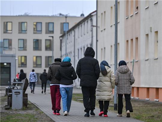 Asylsuchende gehen über das Gelände der Zentralen Erstaufnahmeeinrichtung für Asylbewerber des Landes Brandenburg in Eisenhüttenstadt.