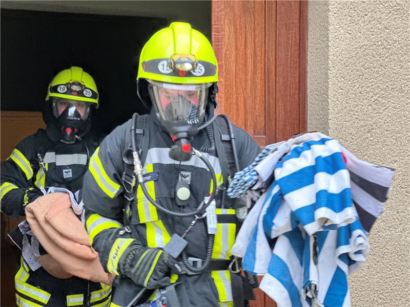 Atemschutzgeräteträger der Feuerwehr Braunlage bringen die angebrannten Wolldecken von der Wäscherei im Keller des Sanatoriums ins Freie.  Fotos: Eggers