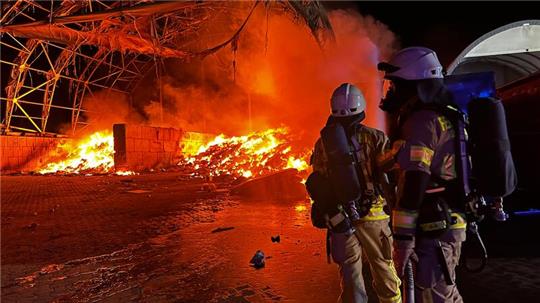 Atemschutzträger der Feuerwehr Goslar vor der brennenden Recyclinghalle.
