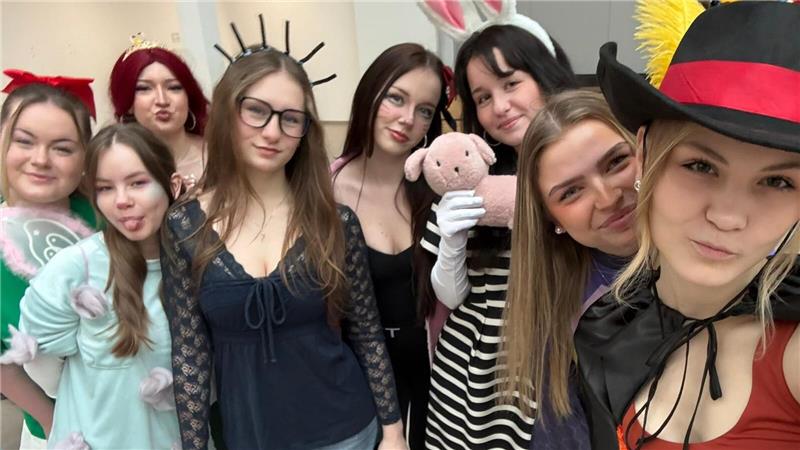 Gruppe von verkleideten Personen, darunter eine mit Hasenohren, eine mit einem pinken Plüschtier und eine mit einem Hut mit gelber Feder.