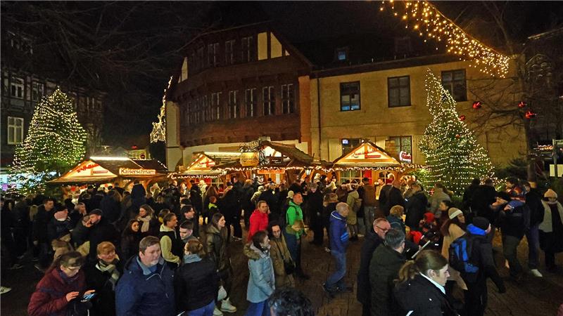 Weihnachtsmarkt bei Nacht mit vielen Besuchern, beleuchteten Ständen und geschmückten Tannenbäumen.