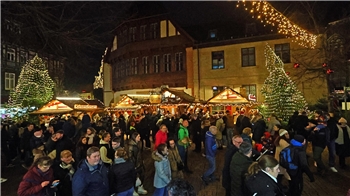 Weihnachtsmarkt bei Nacht mit vielen Besuchern, beleuchteten Ständen und geschmückten Tannenbäumen.