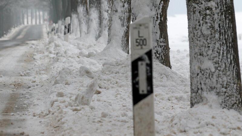 Schneemassen liegen am Rand einer Fahrbahn.