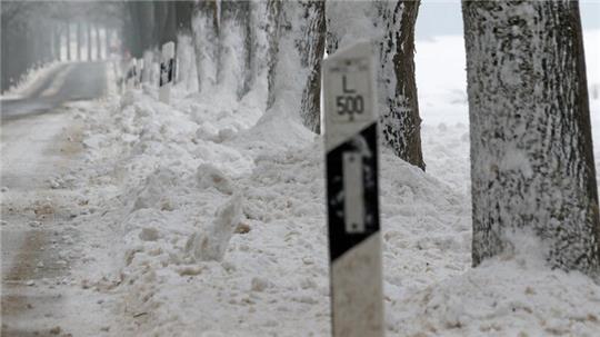 Schneemassen liegen am Rand einer Fahrbahn.