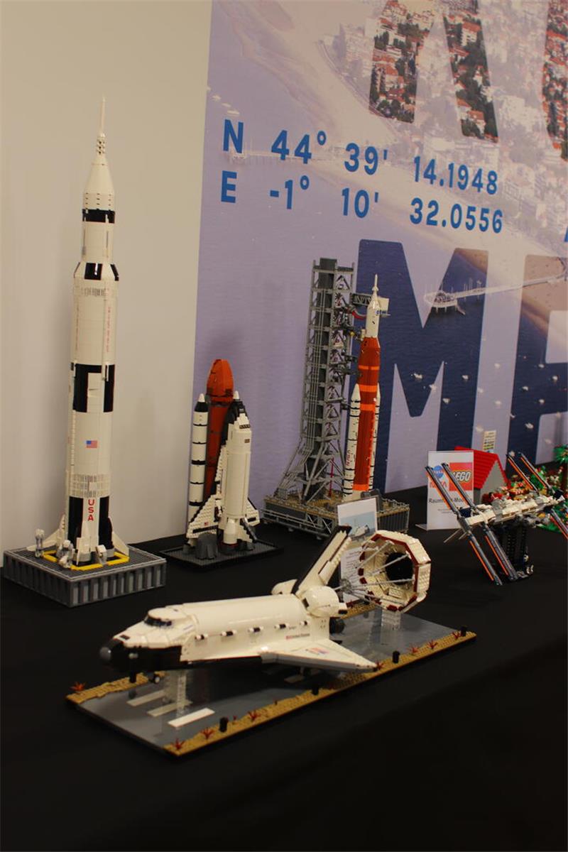 Flugezeuge und Raketen in Modellgröße stehen auf einem Tisch an der Wand.