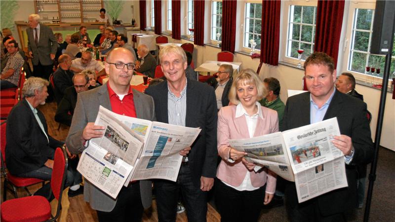 Vier Personen halten in einem vollen Saal Goslarsche Zeitungen in der Hand.