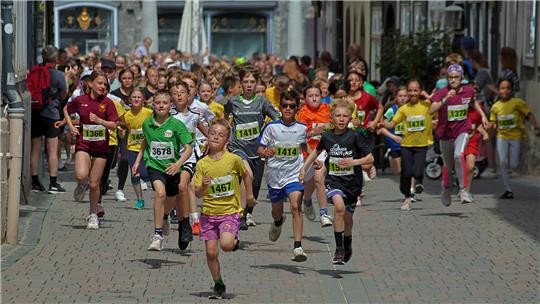 Kinder laufen in einem Altstadtlauf auf gepflasterter Straße zwischen historischen Gebäuden