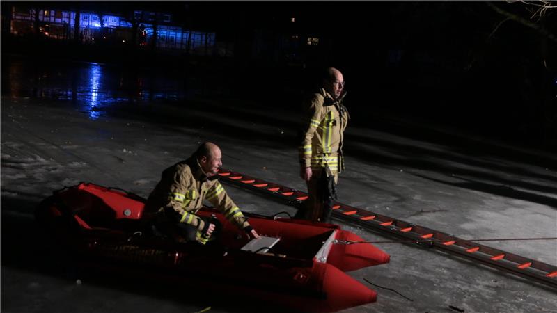 Zwei Einsatzkräfte der Feuerwehr, einen von ihnen in einem roten Schlauchboot, auf dem See.