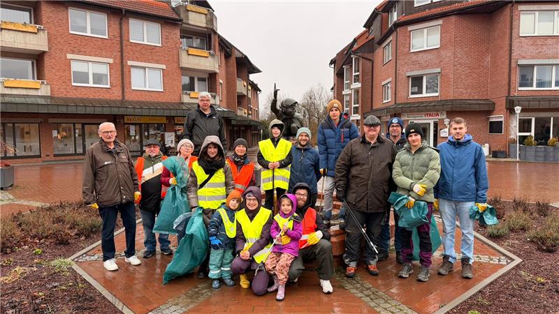„Müllboss“ in Goslar: Skier, Auspuff und „Drogen“ im Müll entdeckt Gruppe von Menschen mit Warnwesten und Handschuhen steht vor einer Statue in einem gepflasterten Platz zwischen Wohngebäuden.