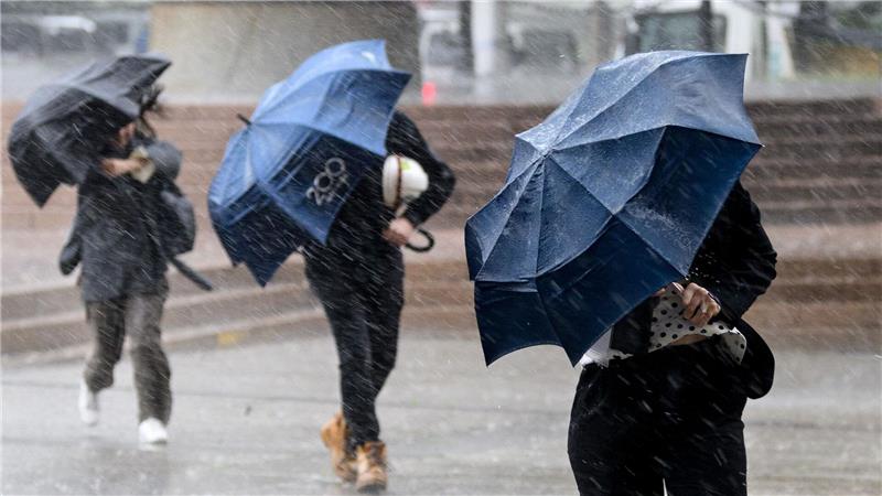 Bilder des Tages Auch in Australien scheint nicht immer die Sonne: Passanten in Sydney schützen sich mit Schirmen vor starkem Regen.