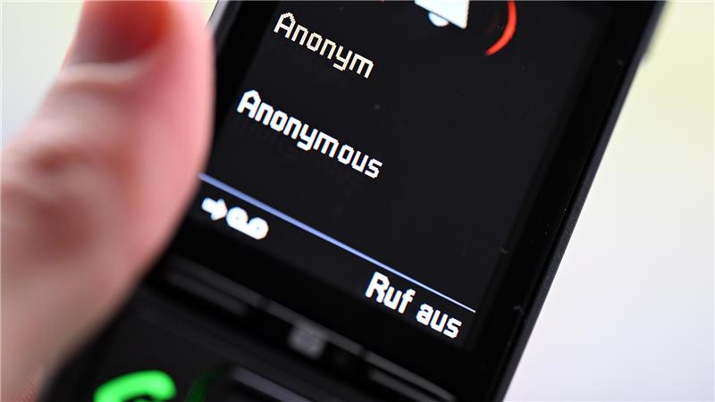 Ein Mann hält ein Festnetz-Telefon, auf dem ein anonymer Anruf eingeht (gestellte Szene). 