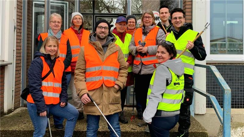 „Müllboss“ in Goslar: Skier, Auspuff und „Drogen“ im Müll entdeckt Gruppe von Personen mit orange- und gelb reflektierenden Warnwesten steht vor einem Gebäude, einige halten Greifzangen.