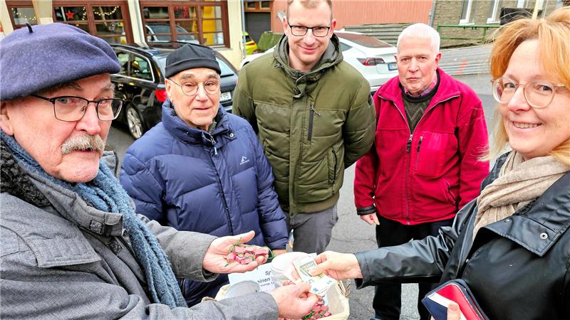 Fünf Menschen stehen mit Geld und GZ-Glücksschweinchen in der Hand in Wildemann an der Tourist-Info.