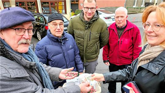 Fünf Menschen stehen mit Geld und GZ-Glücksschweinchen in der Hand in Wildemann an der Tourist-Info.