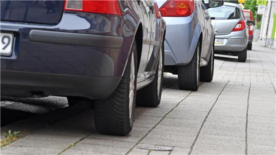Auf Gehwegen parkende Autos versperren Rollstühlen oder Kinderwagen häufig den Weg. (Symbolbild)