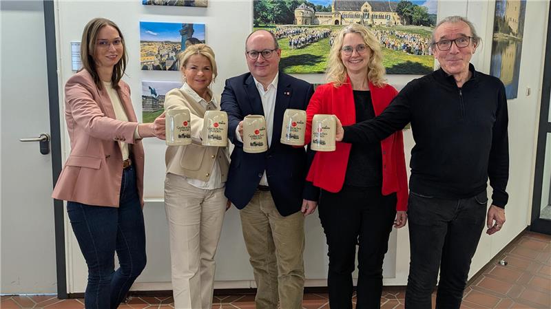Fünf Personen stehen nebeneinander und halten jeweils einen Bierkrug nach vorne