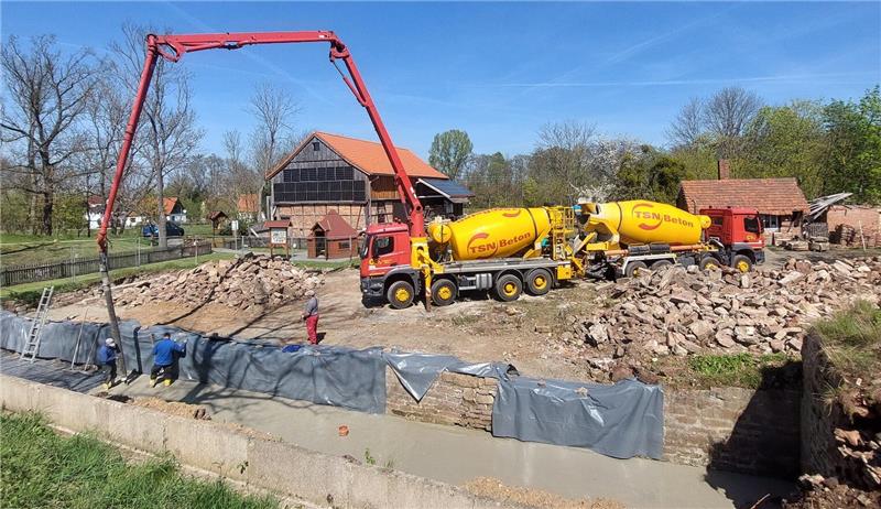 Betonmischer und Betonpumpe zwischen zwei Haufen aus alten Steinen.
