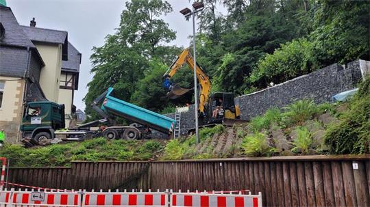 Eine Baustelle, ein Bagger schaufelt Erde auf die Ladefläche eines Lastwagens.