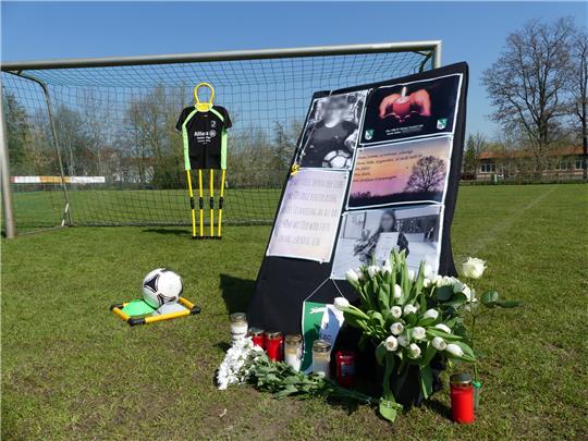 Auf dem Sportplatz von Klötze stehen Kerzen, Blumen und ein Aufsteller zum Gedenken an eine 19-jährige Kezhia H. Foto: Picture Alliance