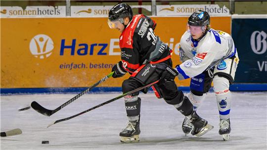 Zwei Eishockeyspieler sind hinter dem Puck her. 