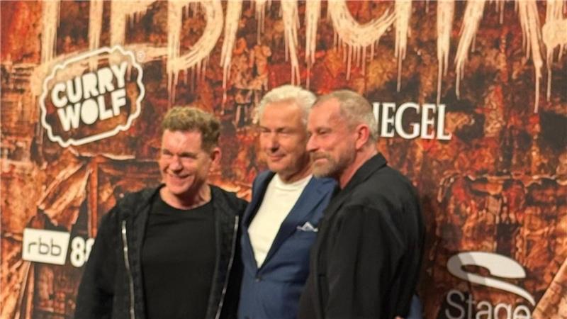 Drei Männer stehen vor einer Wand mit den Logos 'CURRY WOLF', 'rbb 88' und 'Stage'.