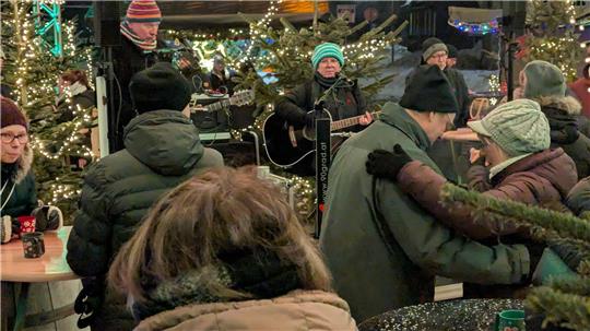 Das Foto zeigt eine Musikgruppe und tanzende Menschen.