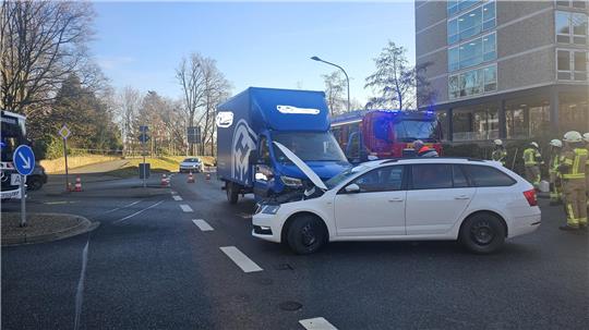 Unfallszene mit einem weißen Kombi und einem blauen Lieferwagen auf einer Kreuzung, mehrere Feuerwehrleute stehen daneben