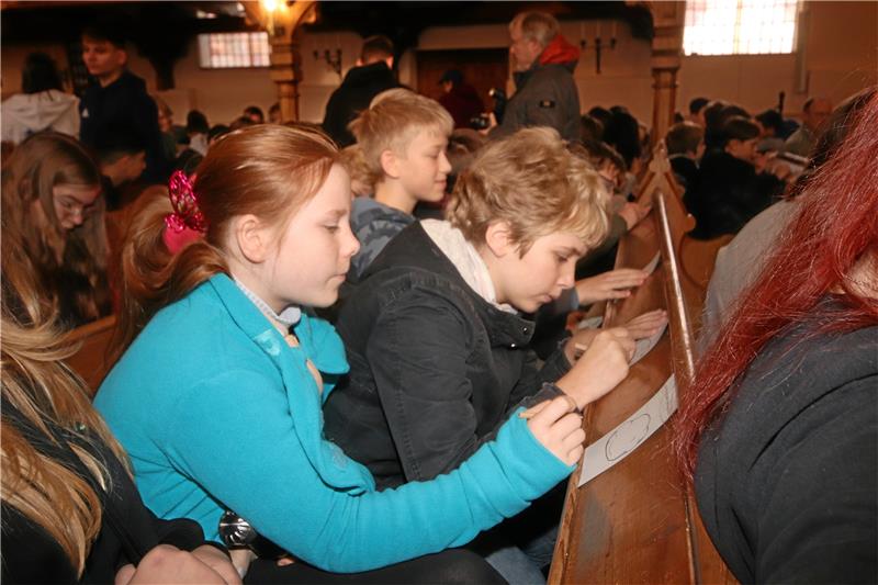 Geständnisse der Schladener Werla-Schüler auf dem Schuldstein Auf der Kirchenbank füllen die Kinder und Jugendlichen die Zettel mit den Geständnissen aus. Foto: Gereke