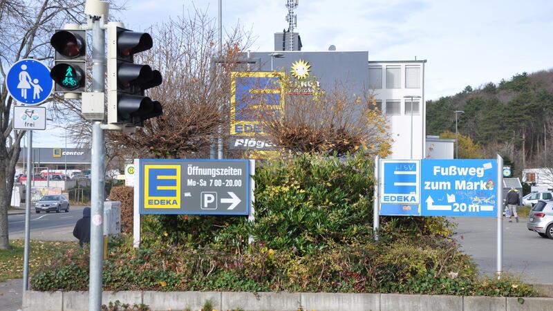 Mehrere Schilder weisen auf den Edeka-Plöger-Markt und dessen Öffnungszeiten hin. 