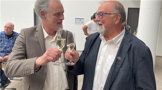 Zum Start des neuen Schulzentrums Goldene Aue stoßen Martin Ehrenberg und Hans-Peter Dreß im Sommer 2024 fröhlich mit Sekt an. 