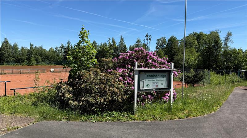 Das Foto zeigt auf der rechten Seite einen asphaltierten Weg und links mehrere Tennisplätze.