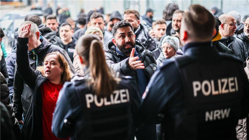 Aufgebrachte Kunden diskutieren vor der Sparkassenfiliale mit Polizeibeamten (Archivfoto)