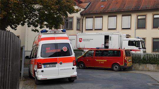 Mehrere Krankenwagen und ein Lkw stehen vor einem Gebäude.