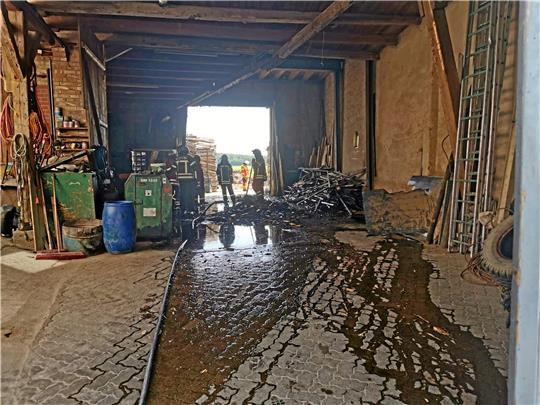 Aufräumarbeiten nach dem Brandeinsatz in Bodenstein: Auf dem Boden fließt das Löschwasser in der Scheune ab, der zusammengekehrte Haufen war in Brand geraten.  Foto: Feuerwehr
